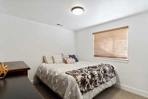 Bedroom with baseboards, visible vents, and dark carpet