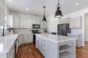 Kitchen featuring range with gas stovetop, high end fridge, light countertops, a kitchen island, and black microwave