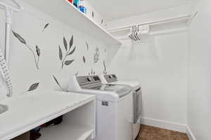 Clothes washing area featuring laundry area, separate washer and dryer, and baseboards