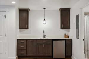 Bar with a sink, hanging light fixtures, and stainless steel dishwasher