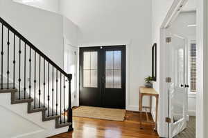 Foyer featuring a healthy amount of sunlight, stairs, wood finished floors, and french doors