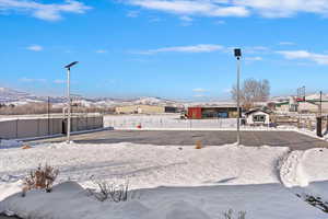 Snowy yard featuring community basketball court, fence, and a mountain view