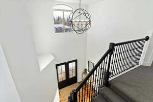 Stairway featuring baseboards, carpet floors, french doors, and a notable chandelier