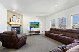 Living area with carpet, a large fireplace, and recessed lighting