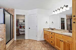 Bathroom with a sink, a spacious closet, a shower stall, and double vanity