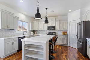 Kitchen with a center island, pendant lighting, open shelves, light countertops, and appliances with stainless steel finishes