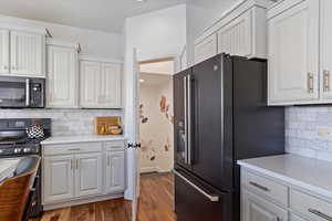 Kitchen featuring light countertops, black appliances, and white cabinetry