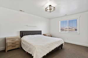 Bedroom with baseboards, visible vents, and dark colored carpet