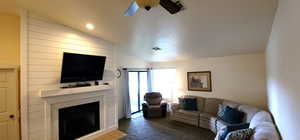 Living area with a large fireplace, vaulted ceiling, ceiling fan, and recessed lighting