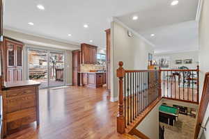 Hall with recessed lighting, an upstairs landing, baseboards, light wood-type flooring, and crown molding