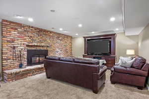 Living room with recessed lighting, a brick fireplace, and light colored carpet