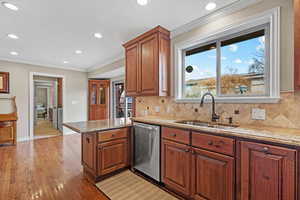 Kitchen with crown molding, tasteful backsplash, a sink, dishwasher, and a peninsula