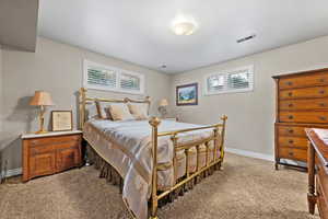 Bedroom with light carpet, visible vents, and baseboards