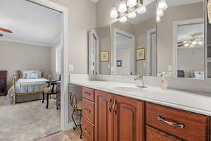 Bathroom featuring connected bathroom, ornamental molding, a ceiling fan, and vanity