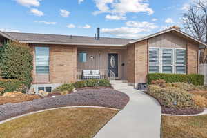 View of front facade featuring covered porch, a front lawn, and brick siding