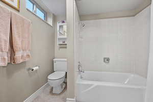 Bathroom with tile patterned flooring, baseboards, shower / tub combination, and toilet