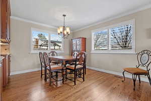 Dining space featuring ornamental molding, an inviting chandelier, and light wood-style floors