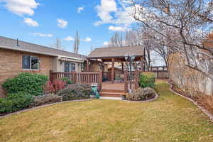 Exterior space with brick siding, roof with shingles, a lawn, and a wooden deck