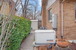 Details featuring fence, a power unit, cooling unit, and brick siding