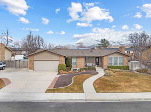 View of front of property with a mountain view, a garage, brick siding, fence, and driveway