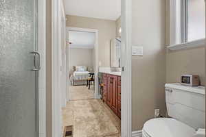 Bathroom featuring visible vents, toilet, a stall shower, vanity, and baseboards