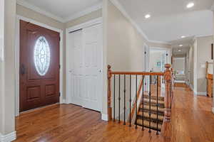 Entrance foyer featuring baseboards, ornamental molding, wood finished floors, and recessed lighting