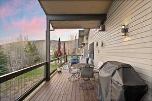 Deck at dusk featuring a grill and outdoor dining space