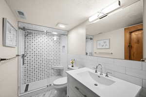 Full bath featuring marble finish floor, visible vents, a textured ceiling, and vanity