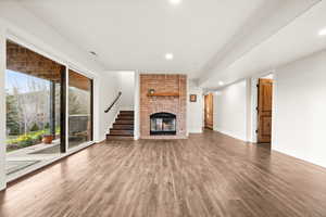 Unfurnished living room with recessed lighting, a fireplace, baseboards, and wood finished floors