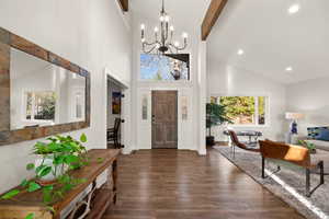 Foyer featuring dark wood finished floors, beamed ceiling, high vaulted ceiling, a notable chandelier, and recessed lighting