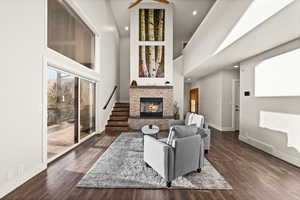 Living room featuring dark wood-style flooring, visible vents, a fireplace, and baseboards