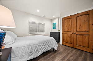 Bedroom with dark wood-style floors, visible vents, and recessed lighting