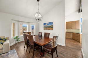 Dining space featuring a chandelier, dark wood-style flooring, high vaulted ceiling, and baseboards