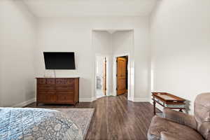 Bedroom with baseboards, dark wood-style flooring, and ensuite bathroom