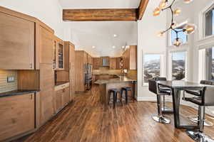 Kitchen with glass insert cabinets, beamed ceiling, a sink, pendant lighting, and backsplash