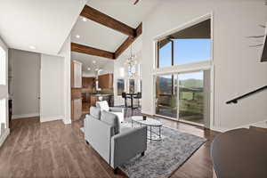 Living area with beam ceiling, an inviting chandelier, dark wood-type flooring, high vaulted ceiling, and baseboards