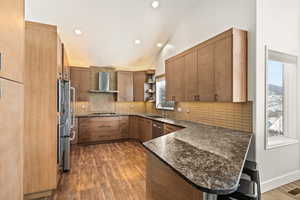 Kitchen featuring decorative backsplash, a peninsula, stainless steel appliances, wall chimney range hood, and open shelves