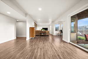 Unfurnished living room with recessed lighting, dark wood-style flooring, and baseboards