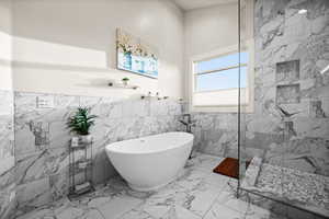 Full bathroom featuring a freestanding bath, marble finish floor, wainscoting, and a marble finish shower