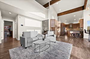 Living room with high vaulted ceiling, dark wood finished floors, beam ceiling, and recessed lighting