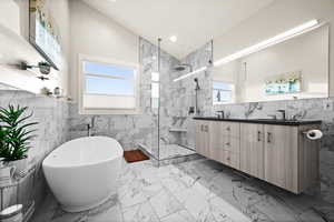 Full bath with a marble finish shower, marble finish floor, vaulted ceiling, a freestanding tub, and tile walls