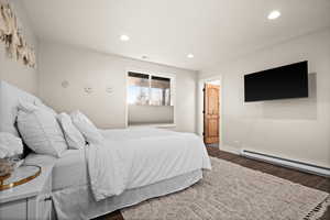 Bedroom with baseboards, baseboard heating, dark wood finished floors, and recessed lighting