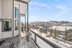 Snow covered deck with a residential view and a mountain view