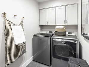 Laundry room featuring cabinet space, washing machine and dryer, and light tile patterned floors