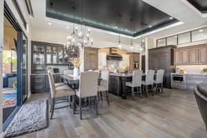 Dining space featuring a towering ceiling, a raised ceiling, and dark wood-type flooring