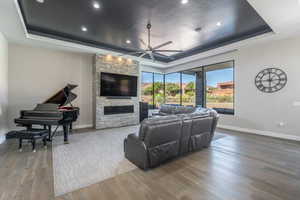 Living room featuring ceiling fan, a tray ceiling, and wood finished floors