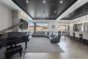 Living room featuring a chandelier, a tray ceiling, recessed lighting, and wood finished floors