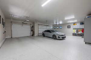 Garage featuring baseboards, water heater, and a garage door opener