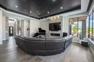 Living room featuring a tray ceiling, a fireplace, and wood finished floors