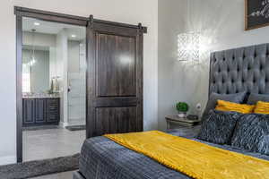 Bedroom featuring a barn door, baseboards, and connected bathroom